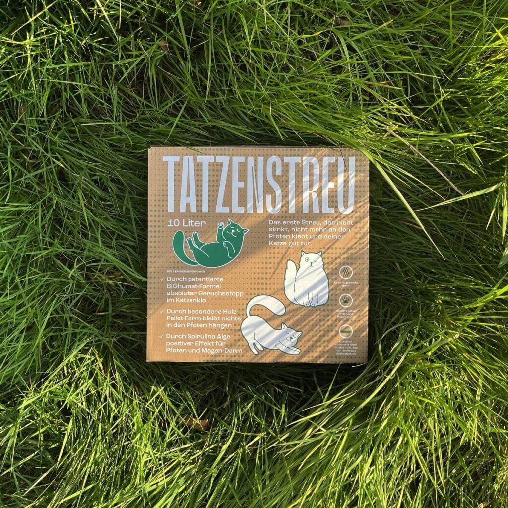 Ein Karton TATZENSTREU Katzenstreu-Pellets aus nachhaltigem Holz im Gras liegend