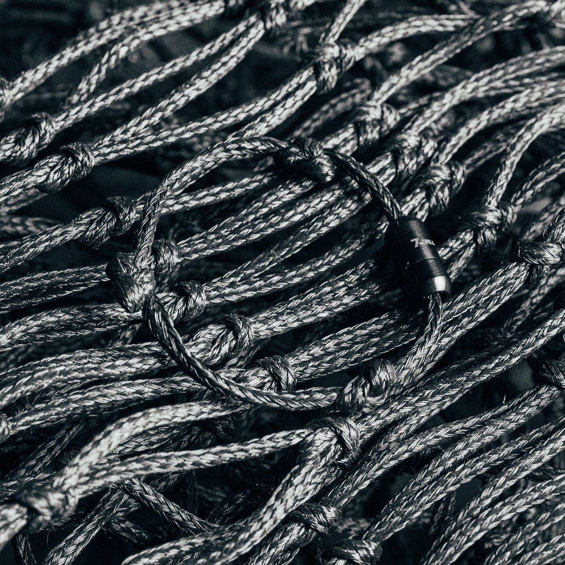 BRACENET Upcycling Armband Black Sea von Fritz Meinecke für 7 vs. Wild liegt auf dem schwarzen Fischernetz