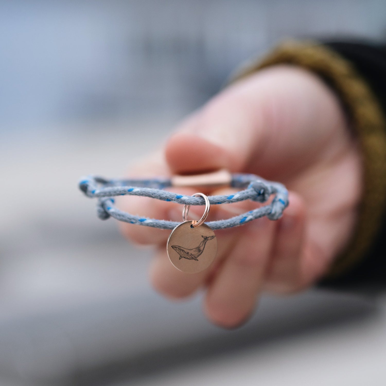 Person hält ein BRACENET Upcycling Armband mit einem roségoldenen Edelstahlanhänger