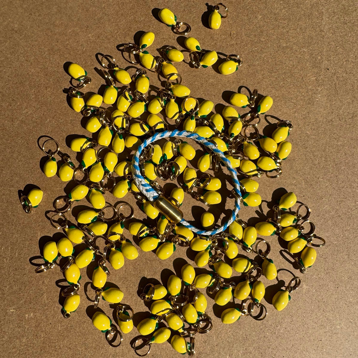Almalfi Bracenet Bracelet aus Fischernetz in weiß und blau mit Edelstahl Magnetverschluss und einem Zitronenanhänger. Weitere viele Zitronenanhänger