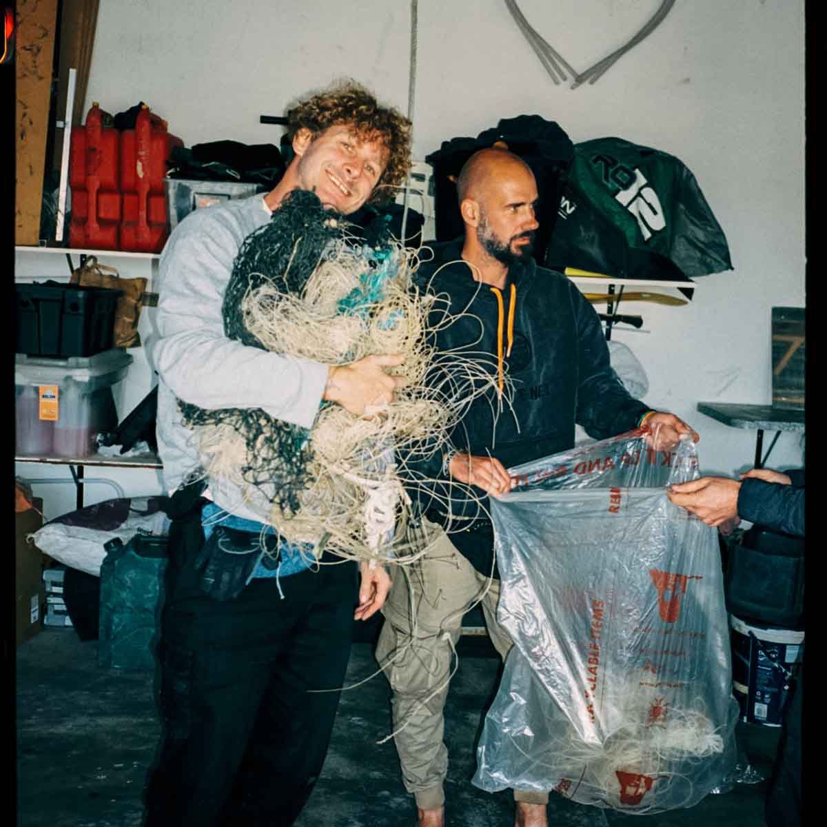 Benjamin von BRACENET hält einen großen Beutel geöffnet, in den Malte Zierden gesammelte Fischernetze und Langleinen packt.