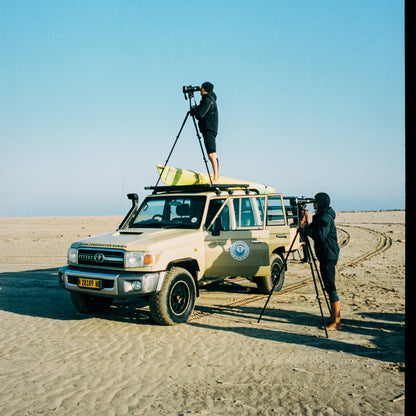 Zwei Personen stehen mit einem Auto am Strand und halten durch Ferngläser nach den Robben Ausschau. 