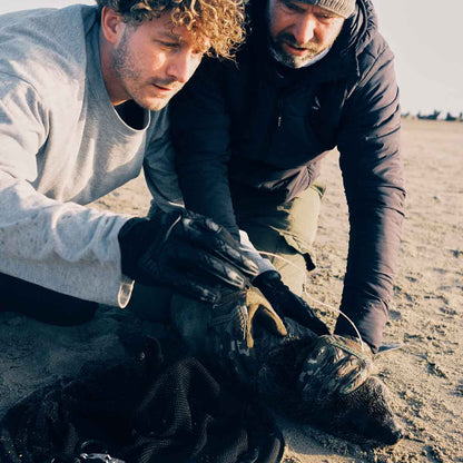Malte Zierden ist mit einer weiteren persin am Strand und befreit eine Robbe aus einem Fischernetz. 