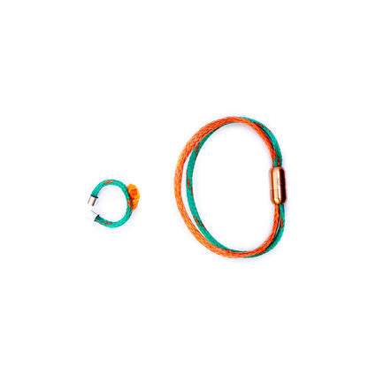 August Bracenet Phuket Armband aus Fischernetz mit einem Strang Fischernetz in Grün mit Highlights in Orange, einem Strang Fischernetz in Orange und einem Magnetverschluss in Roségold und August Ring Kohg Phi Phi aus Fischernetz in Grün mit Highlights in Orange und einem orangenen Knoten mit Endkappen in Silber.