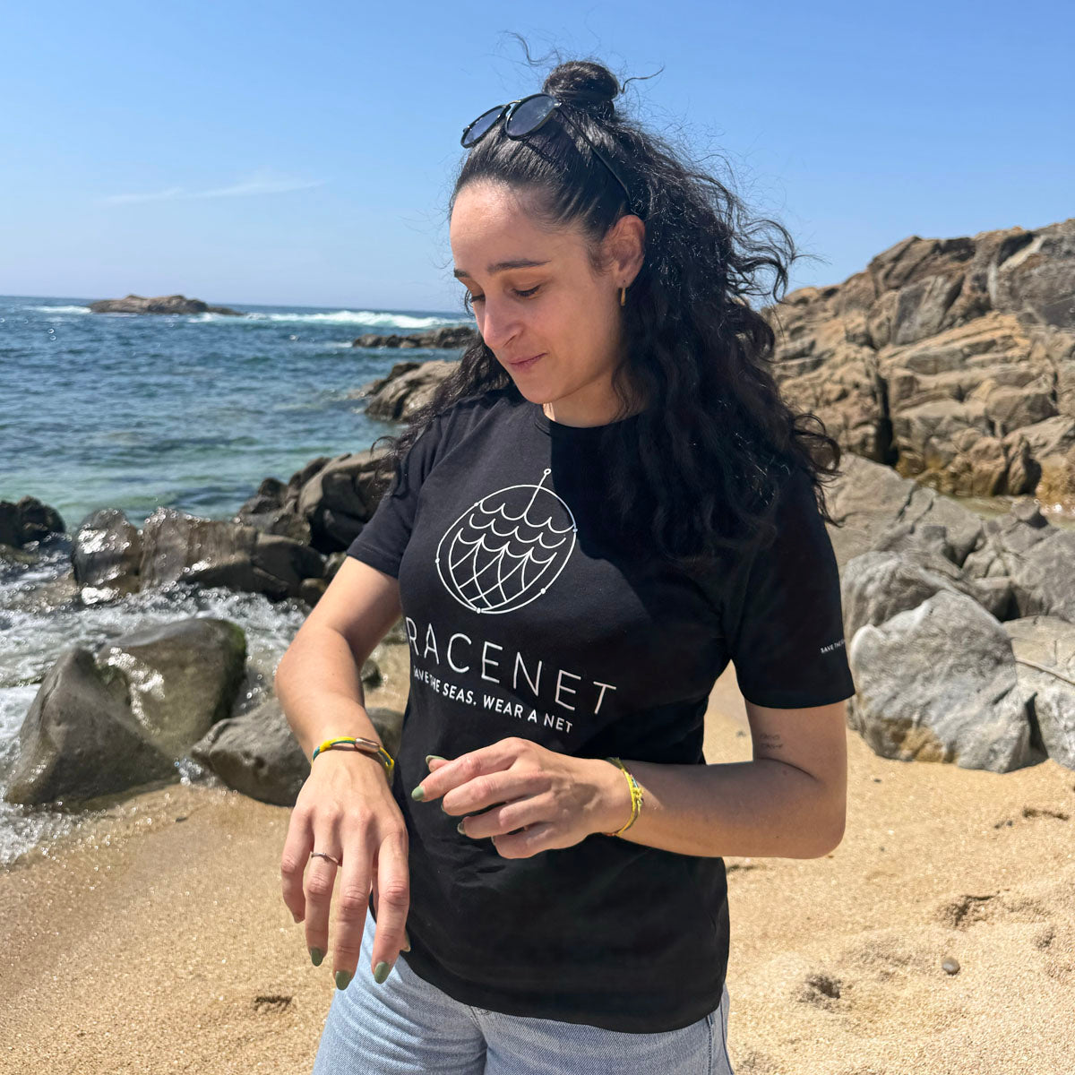 Person ist am Strand und trägt das Mai Bracenet Mayotte's Lagoon aus Fischernetz in Hellblau und Gelb mit Knoten und mit Bajonettverschluss in Silber am Handgelenk.