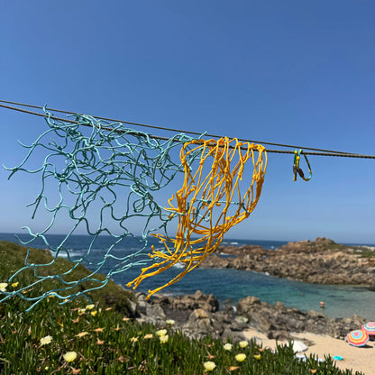 Mai Bracenet Mayotte's Lagoon aus Fischernetz in Hellblau und Gelb mit Knoten und mit Bajonettverschluss in Silber oder Schwarz hängen gemeinsam mit Fischernetzen an einer Leine. 