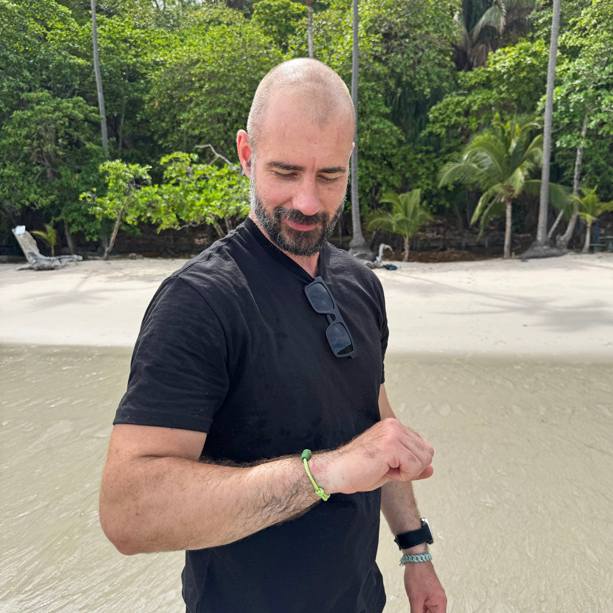 Person trägt das Juni Bracenet Bismarck Sea aus Fischernetz in Hellgrün mit Magnetverschluss aus eingeschmolzenen Fischernetzen in Grün am Handgelenk am Strand.   