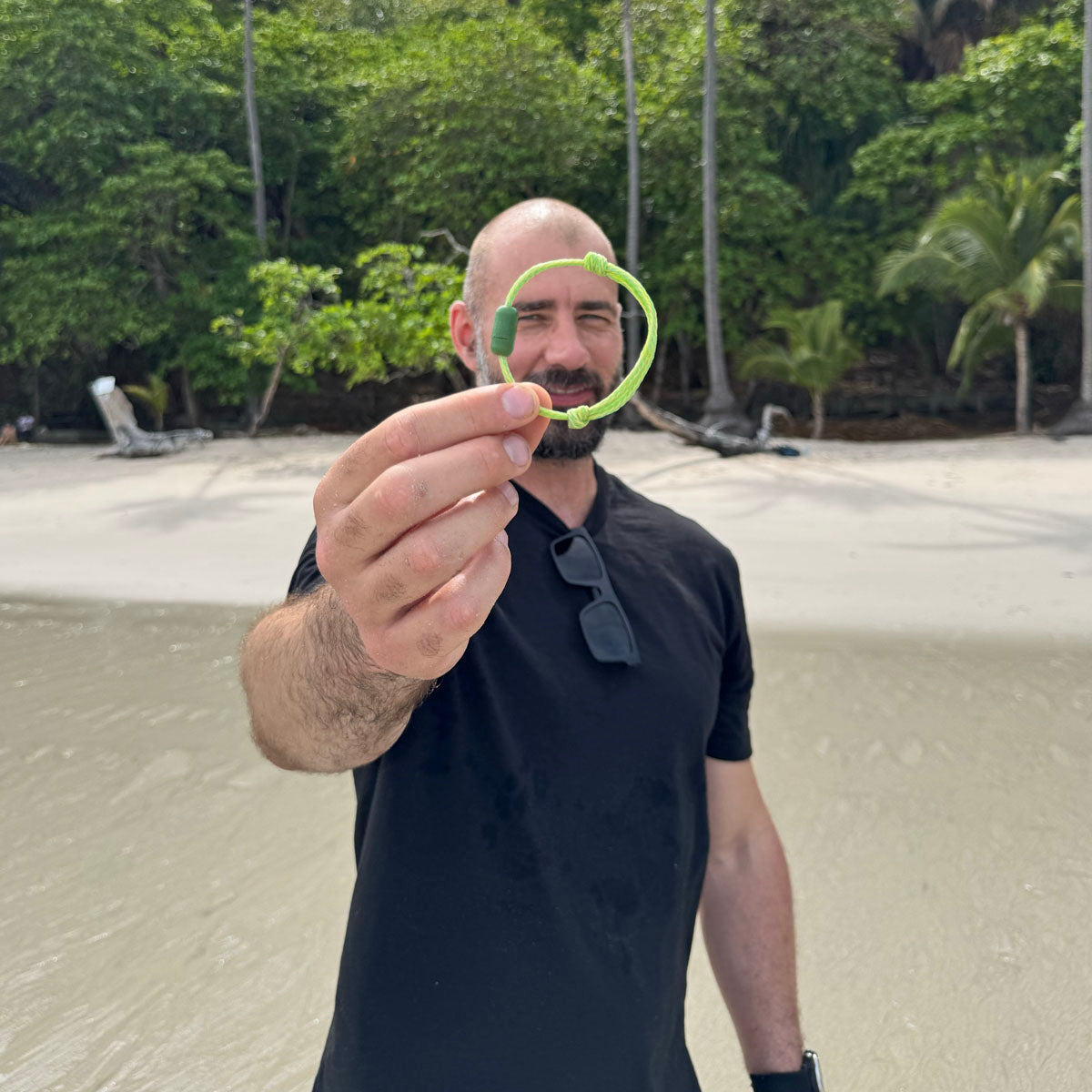 Person hält das Juni Bracenet Bismarck Sea aus Fischernetz in Hellgrün mit Magnetverschluss aus eingeschmolzenen Fischernetzen in Grün vor sich in der Hand. 