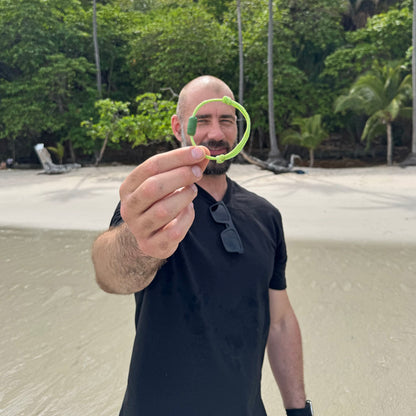 Person hält das Juni Bracenet Bismarck Sea aus Fischernetz in Hellgrün mit Magnetverschluss aus eingeschmolzenen Fischernetzen in Grün vor sich in der Hand. 