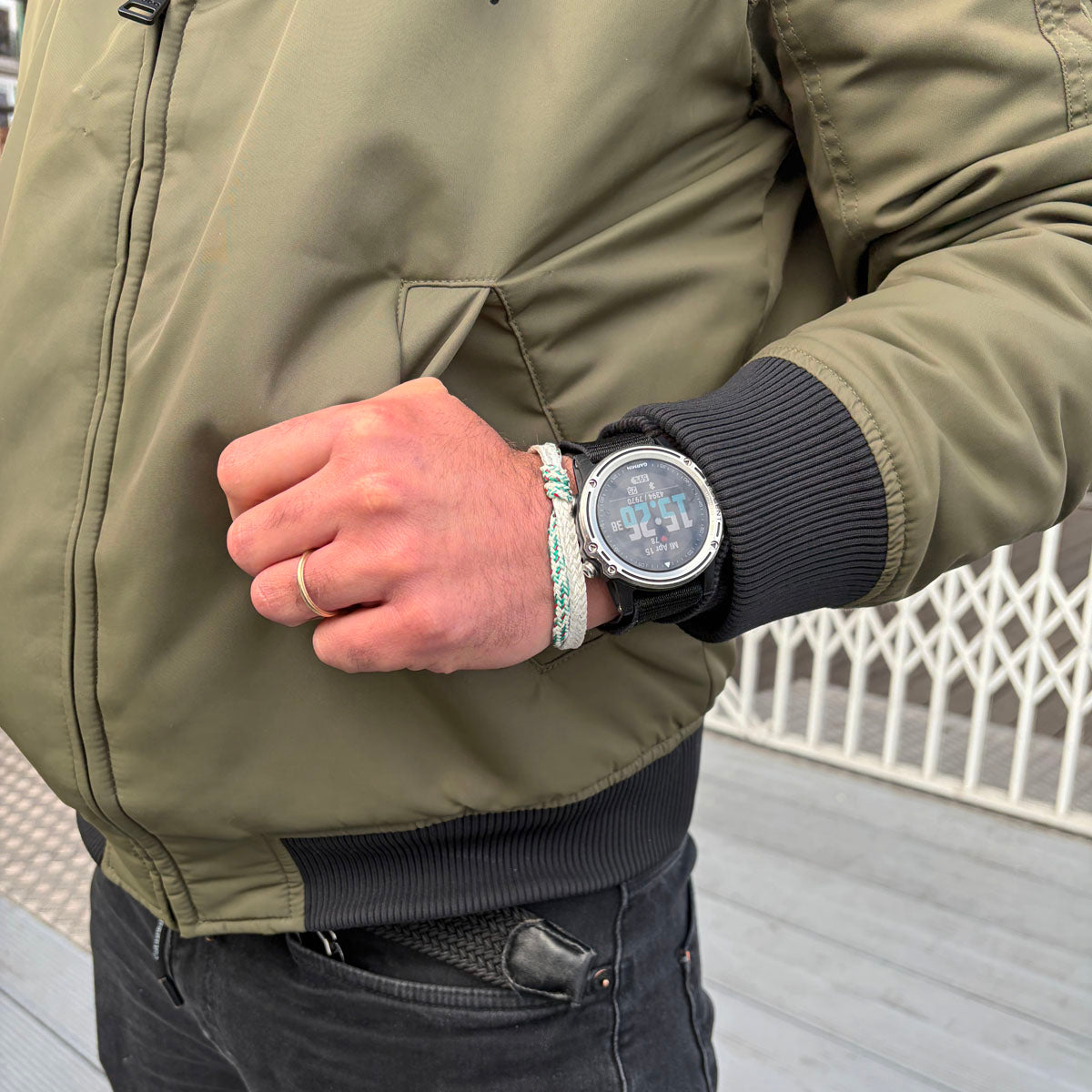 Person trägt das Enard Bay Bracenet aus Fischernetz in Weiß und Grün mit Umwicklung in der Mitte und mit Bajonettverschluss in Silber am Handgelenk. 