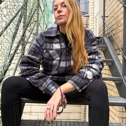 Person sitzt auf einer Treppe und trägt das BRACENET Armband aus Fischernetz in Lila mit Magnetverschluss in Gold und einem Otter-Anhänger in Gold am Handgelenk. 