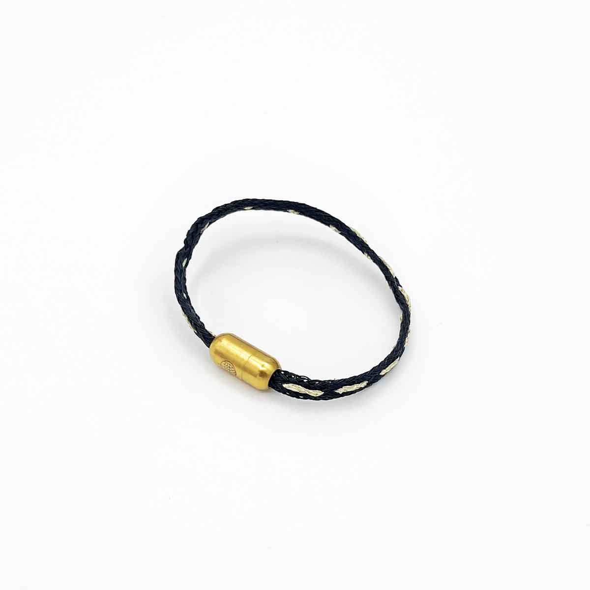 Das BRACENET Glam Edition Armband aus schwarzem Fischernetz mit goldenem Faden durchzogen und goldenem Magnetverschluss.