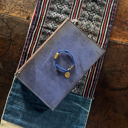 Sicilia, Sizilien Bracenet Bracelet aus Fischernetz in blau und gold mit Edelstahl Magnetverschluss und einem Medusa Anhänger auf einem Buch