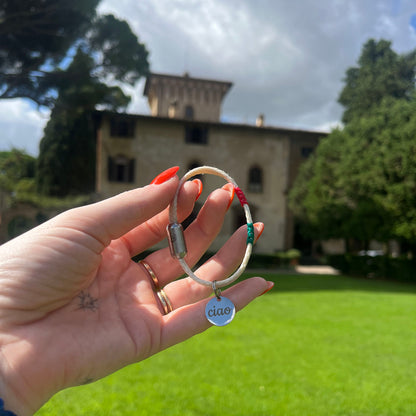 Italy, Italien Bracenet Bracelet  aus ehemaligem Fischernetz in Weiß mit roten und grünen Akzenten mit Edelstahl Magnetverschluss und einem Edelstahlanhänger mit Ciao Gravur in der Hand gehalten