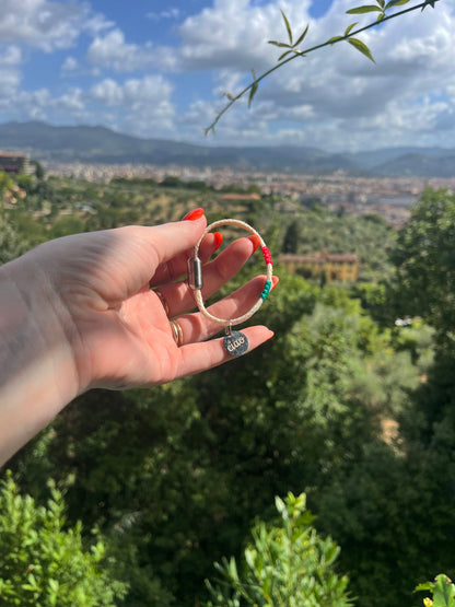 Italy, Italien Bracenet Bracelet  aus ehemaligem Fischernetz in Weiß mit roten und grünen Akzenten mit Edelstahl Magnetverschluss und einem Edelstahlanhänger mit Ciao Gravur in der Hand gehalten