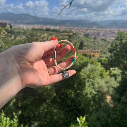 Italy, Italien Bracenet Bracelet  aus ehemaligem Fischernetz in Weiß mit roten und grünen Akzenten mit Edelstahl Magnetverschluss und einem Edelstahlanhänger mit Ciao Gravur in der Hand gehalten