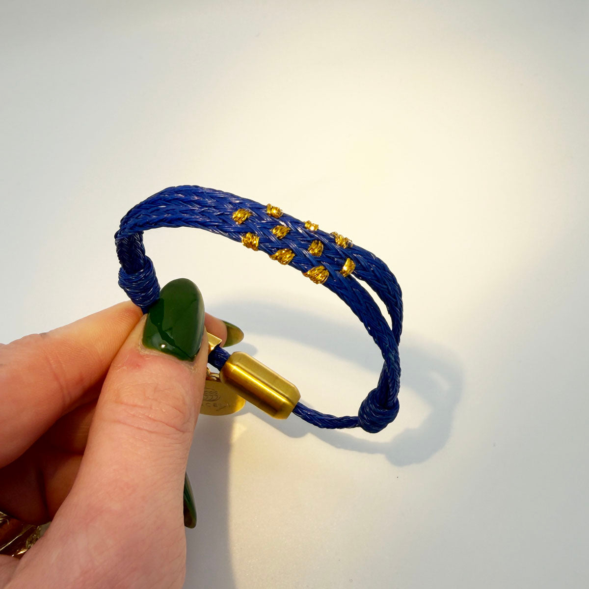 Sicilia, Sizilien Bracenet Bracelet aus Fischernetz in blau und gold mit Edelstahl Magnetverschluss und einem Medusa Anhänger in der Hand gehalten