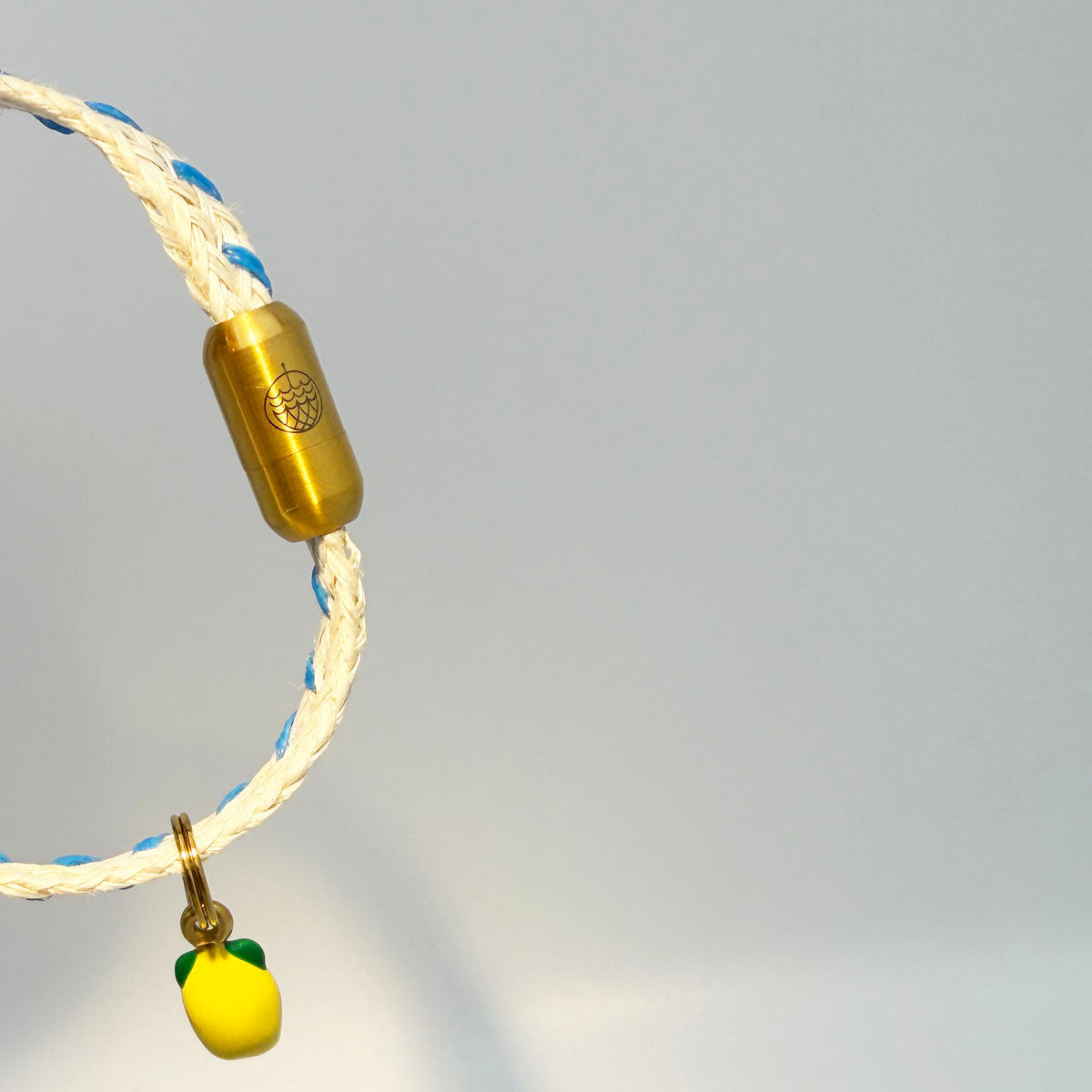 Almalfi Bracenet Bracelet aus Fischernetz in weiß und blau mit Edelstahl Magnetverschluss und einem Zitronenanhänger angeschnitten