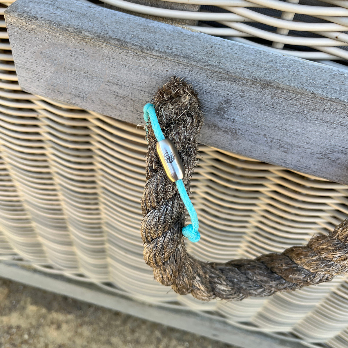 Das BRACENET Upcycling Armband Glacier Bay aus eisblauen Fischernetzen mit 2 Knoten und silbernen Bajonettverschluss hängt an einem Korb
