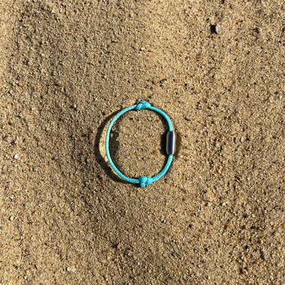 Das BRACENET Upcycling Armband Glacier Bay aus eisblauen Fischernetzen mit 2 Knoten und silbernen Bajonettverschluss liegt im Sand