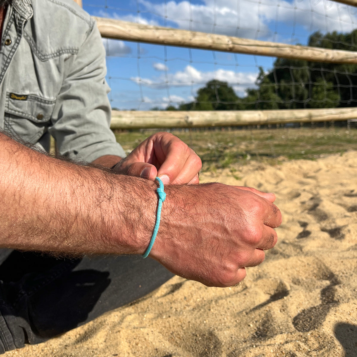 Person trägt das BRACENET Upcycling Armband Glacier Bay aus eisblauen Fischernetzen mit silbernen Bajonettverschluss am Handgelenk und öffnet es