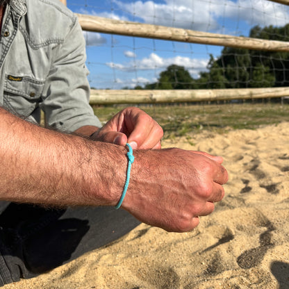 Person trägt das BRACENET Upcycling Armband Glacier Bay aus eisblauen Fischernetzen mit silbernen Bajonettverschluss am Handgelenk und öffnet es