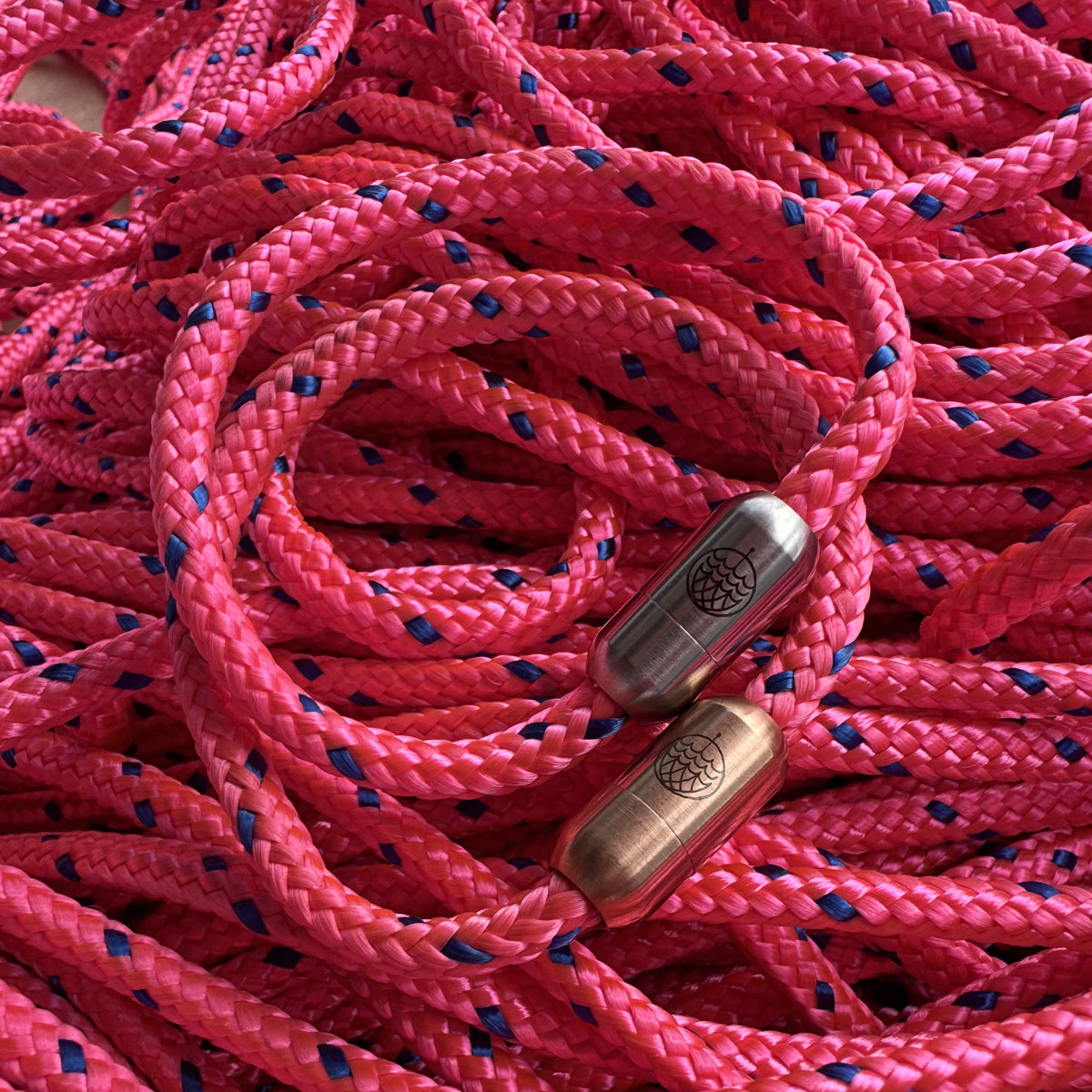 Zwei Gulf of Bothnia Bracenets aus Fischernetz in pink mit Magnetverschluss in Roségold und Silber liegen auf dem Fischernetz. 