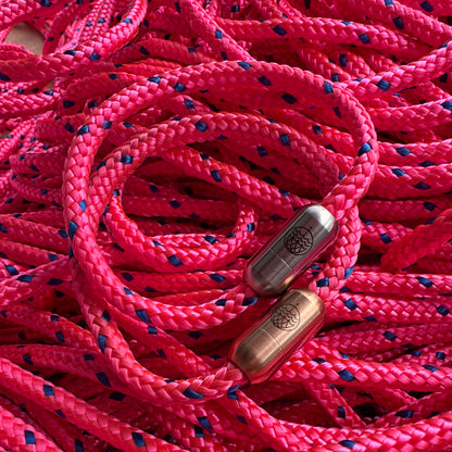 Zwei Gulf of Bothnia Bracenets aus Fischernetz in pink mit Magnetverschluss in Roségold und Silber liegen auf dem Fischernetz. 