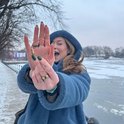 Person hält das Februar Bracenet Amur Bay aus lachsfarbenen Fischernetz mit roten Dolly Ropes verziert und mit roségoldenen Magnetverschluss vor sich und lacht.