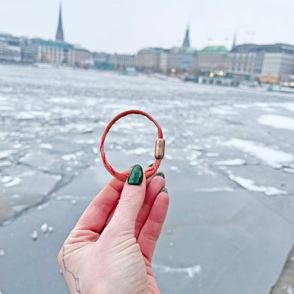 Person hält das Februar Bracenet Amur Bay aus lachsfarbenen Fischernetz mit roten Dolly Ropes verziert und mit roségoldenen Magnetverschluss in der Hand. 