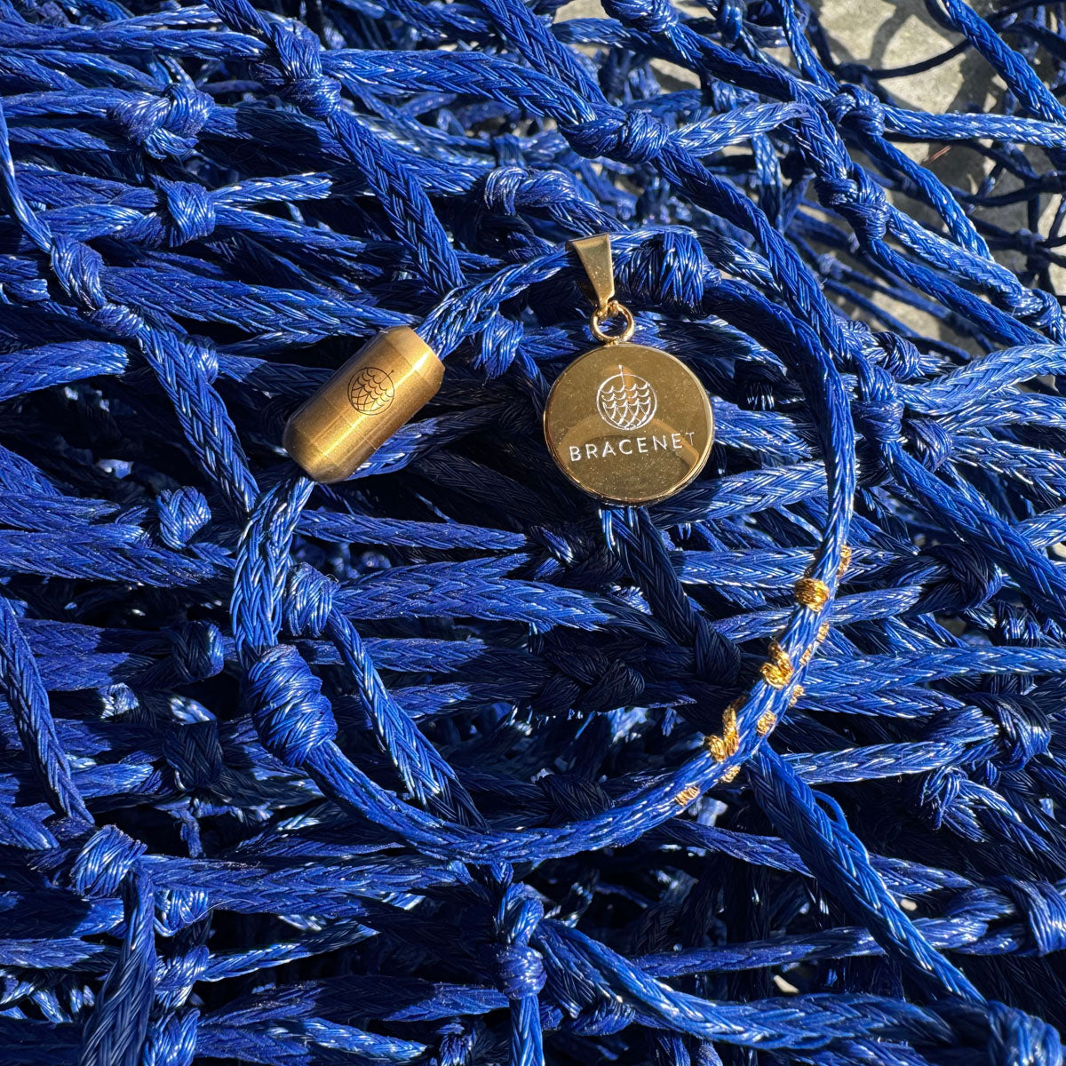 Sicilia, Sizilien Bracenet Bracelet aus Fischernetz in blau und gold mit Edelstahl Magnetverschluss und einem Medusa Anhänger mit Fischernetz im Hintergrund