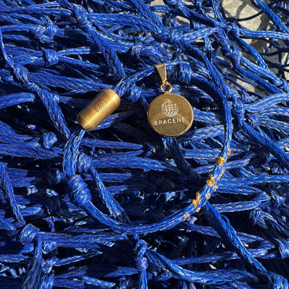 Sicilia, Sizilien Bracenet Bracelet aus Fischernetz in blau und gold mit Edelstahl Magnetverschluss und einem Medusa Anhänger mit Fischernetz im Hintergrund