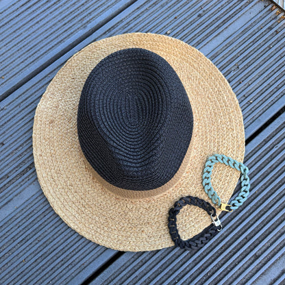SeaChain Bracenets in 3D Druck aus alten Fischernetzen hergestellt in Blassgrün mit kleinem Clip Karabiner in Gold und Silber liegen auf einem Sonnenhut. 