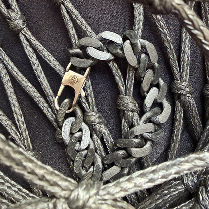 SeaChain Bracenet in 3D Druck aus alten Fischernetzen hergestellt in Schwarz mit kleinem Clip Karabiner in Silber liegt auf Fischernetzen.
