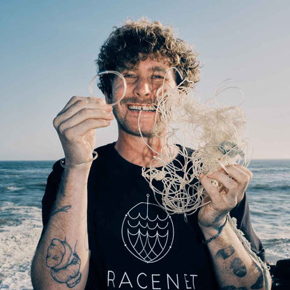 Malte Zierden hält in einer Hand das Alles für die Tiere immer - Robbe "Walvis" Armband aus transparenten Langleinen von BRACENET mit Drehverschluss in silber und "Alles für die Tiere, immer" Gravur mit Robben-Motiv und in der anderen Hand die unverarbeiteten Langleinen. 