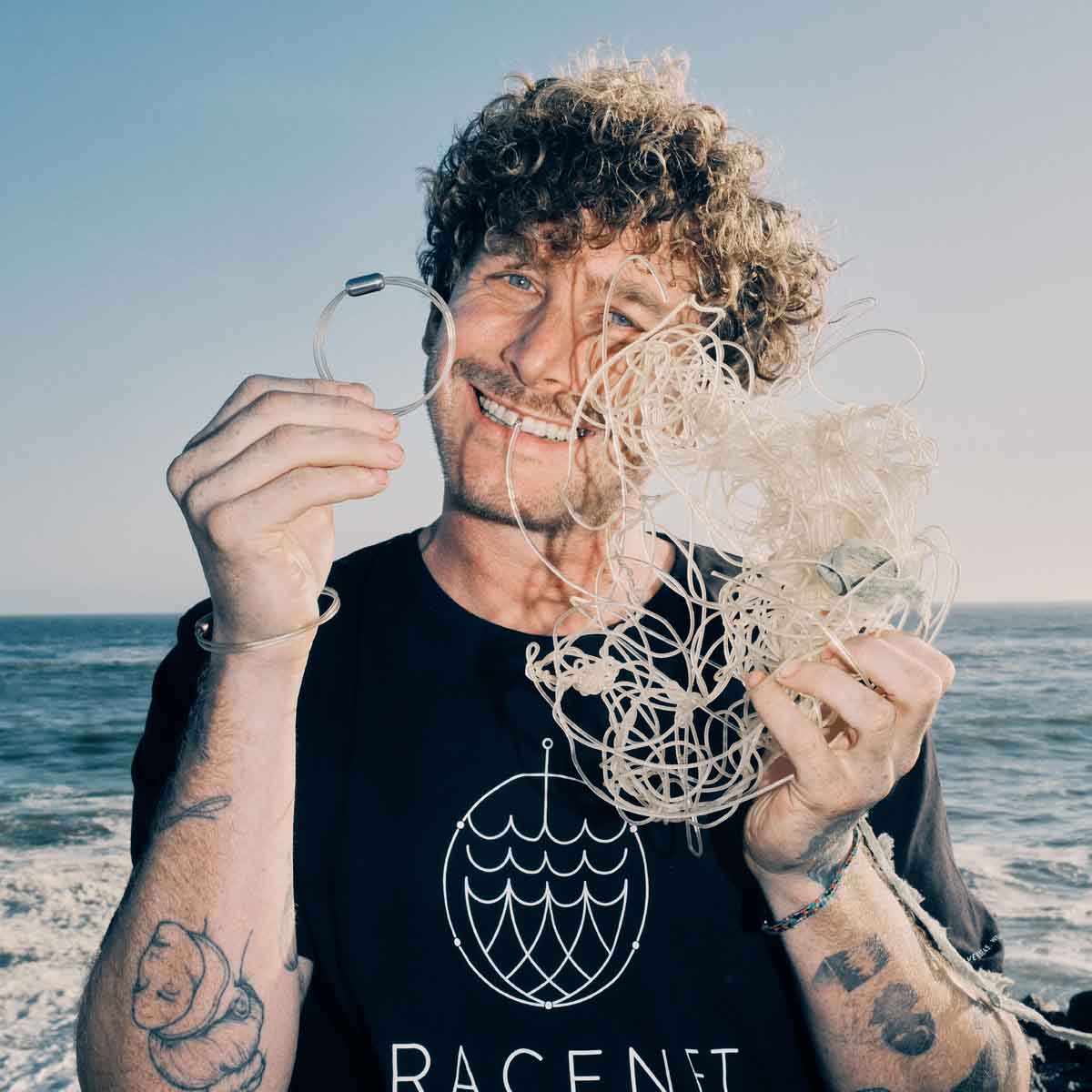 Malte Zierden hält in einer Hand das Alles für die Tiere immer - Robbe "Walvis" Armband aus transparenten Langleinen von BRACENET mit Drehverschluss in silber und "Alles für die Tiere, immer" Gravur mit Robben-Motiv und in der anderen Hand die unverarbeiteten Langleinen. 