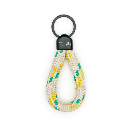 Sea Shepherd X BRACENET x humanvoll Schlüsselanhänger mit schwarzer Kappe mit dem Sea Shepherd und humanvoll Logo aus weißem Fischereiseil mit gelben und grünen Akzenten