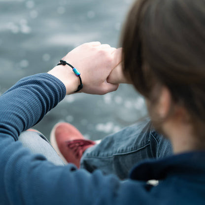 Person trägt das handgefertigte Armband aus Geisternetzen von BRACENET am Handgelenk mit buntem Magnetverschluss.