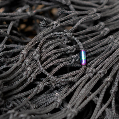 Schwarzes BRACENET Armband Black Sea mit buntem Magnetverschluss liegt auf dem alten Fischernetz