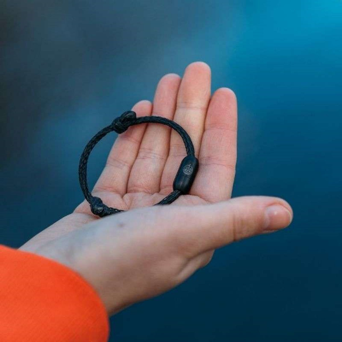 Person hält das BRACENET Upcycling Armband Black Sea aus alten Fischernetzen in der Hand