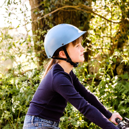 Mädchen trägt Dashel x BRACENET Kids' Sea Shepherd Fahrradhelm in blau mit Blue Whale Logo.