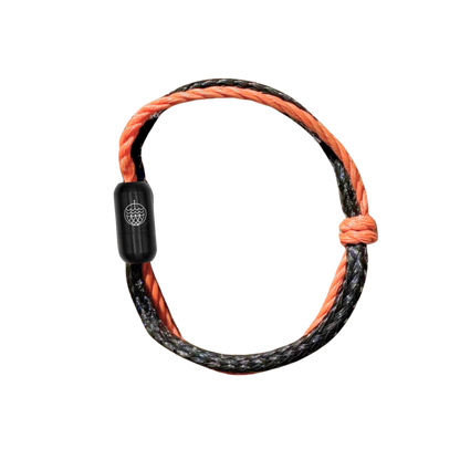 Oktober Bracenet Cardigan Bay aus einem Strang Fischernetz in Schwarz und einem Strang Fischernetz in Orange, verbunden mit einem Knoten und einem Magnetverschluss in Schwarz. 