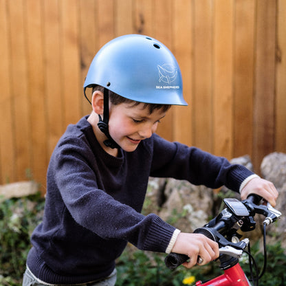 Junge trägt Dashel x BRACENET Kids' Sea Shepherd Fahrradhelm in blau mit Blue Whale Logo.