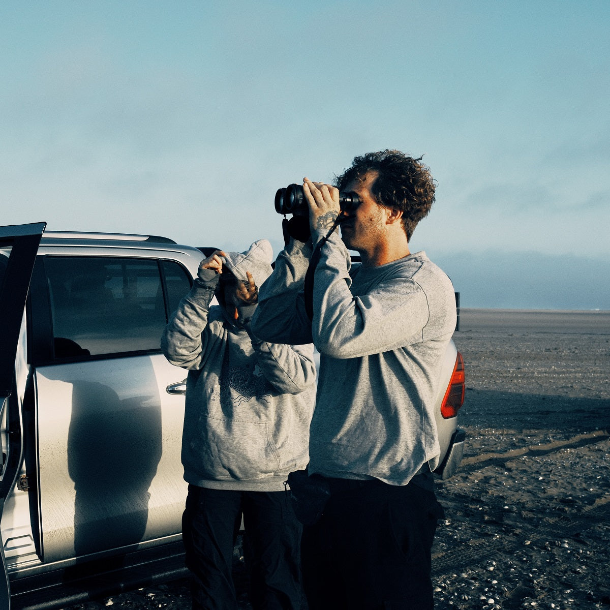 Malte Zierden steht mit der OCN am Strand von Namibia und beobachtet die Robben mit einem Fernglas aus der Ferne, ob sie von Fischernetzen gefährdet sind
