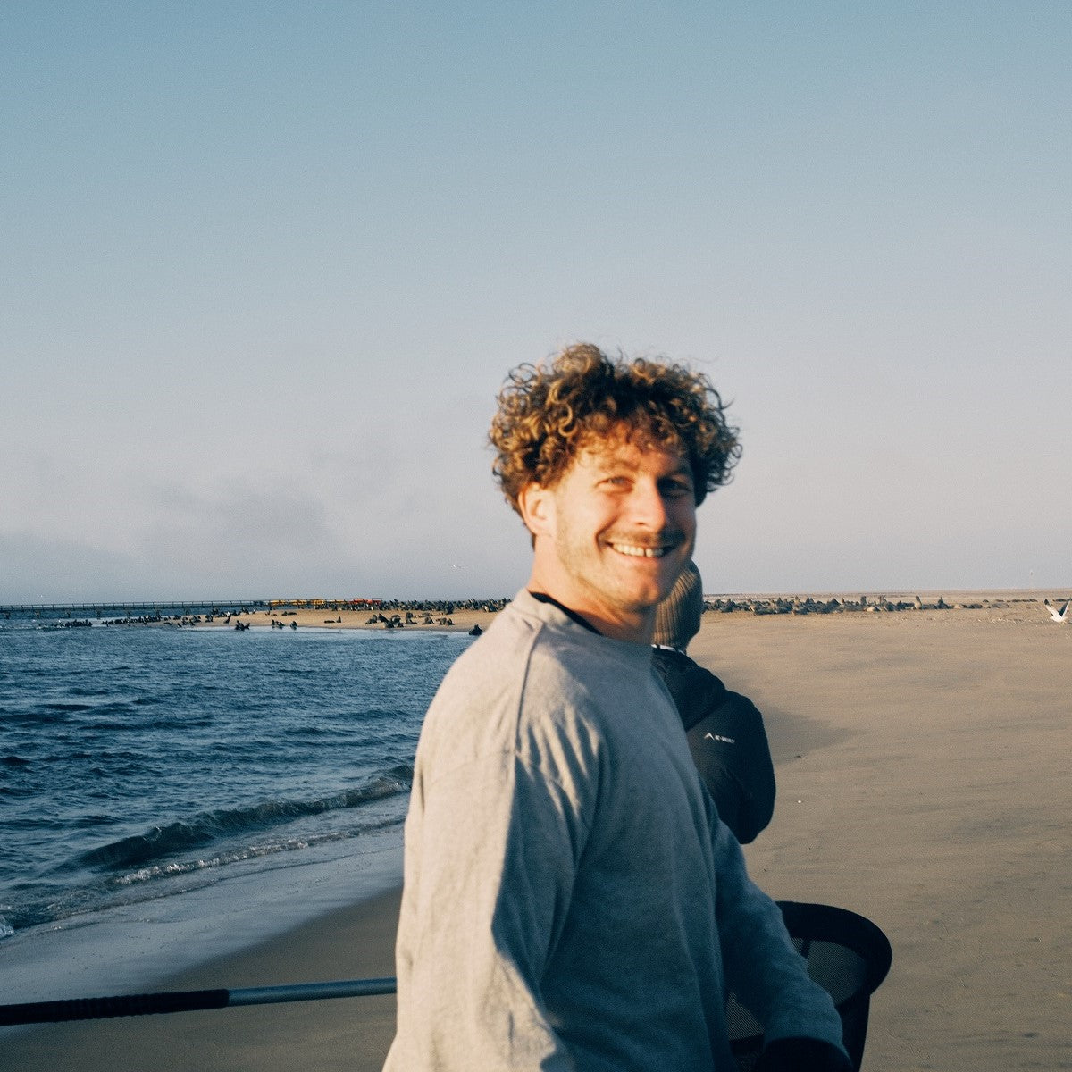 Malte Zierden läuft am Strand von Namibia entlang, dreht sich um und lacht in die Kamera
