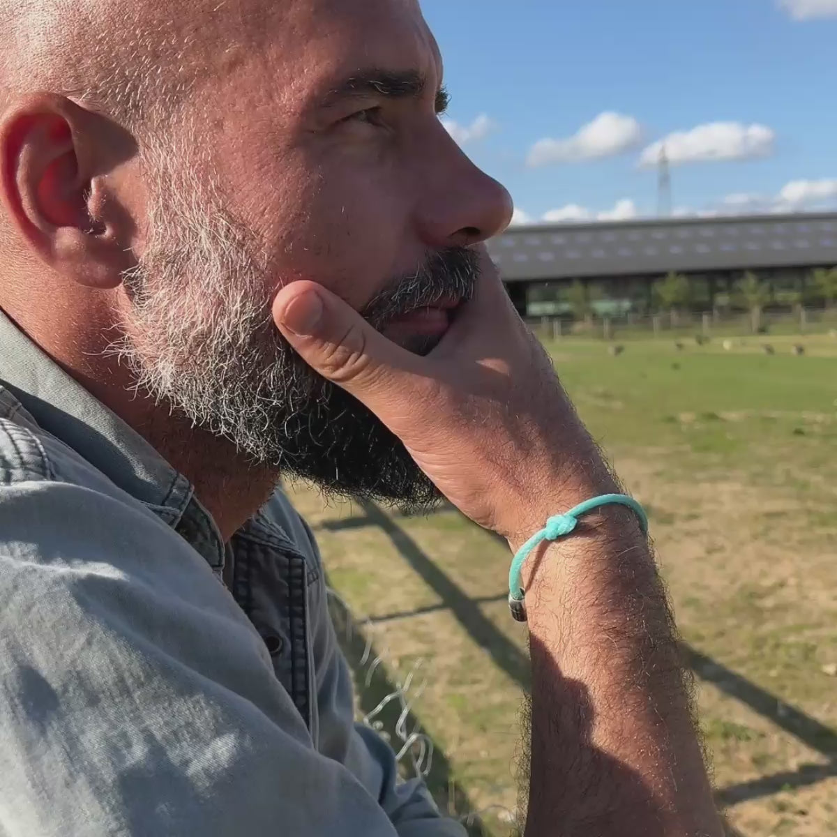 Video von Person, die das BRACENET Upcycling Armband Glacier Bay aus eisblauen Fischernetzen und 2 Knoten mit silbernen Bajonettverschluss am Handgelenk trägt und in die Ferne schaut