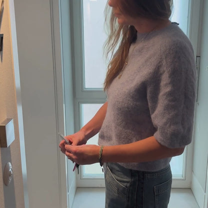 Person nutzt den BRACENET Karten- und Schlüsselhalter mit ausziehbarer Zugrolle, BRACENET Logo, Schnürung aus Red Sea Fischernetz und schwarzem Karabiner. Der Schlüsse- und Kartenhalter ist an der Gürtelschlaufe der Jeans befestigt und die Person zieht die Karte nach vorn um amit die Zimmertür zu öffnen. 